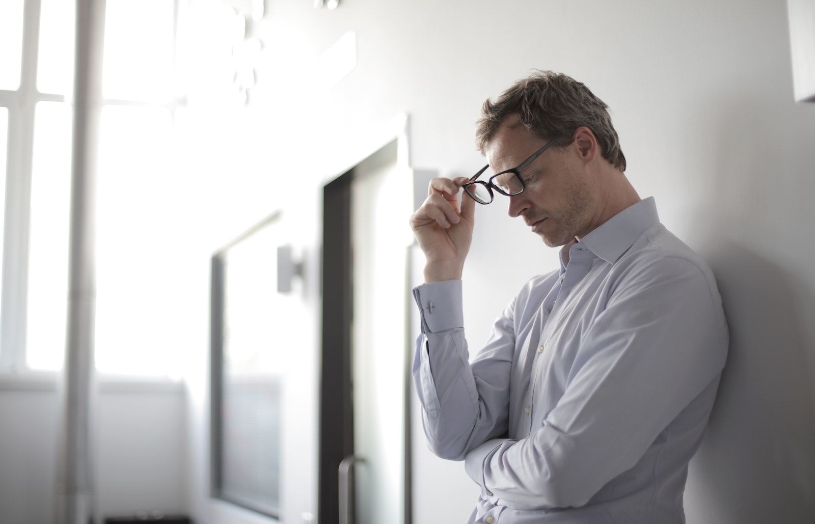 Photo Of Man Holding Black Eyeglasses as he looks stressed