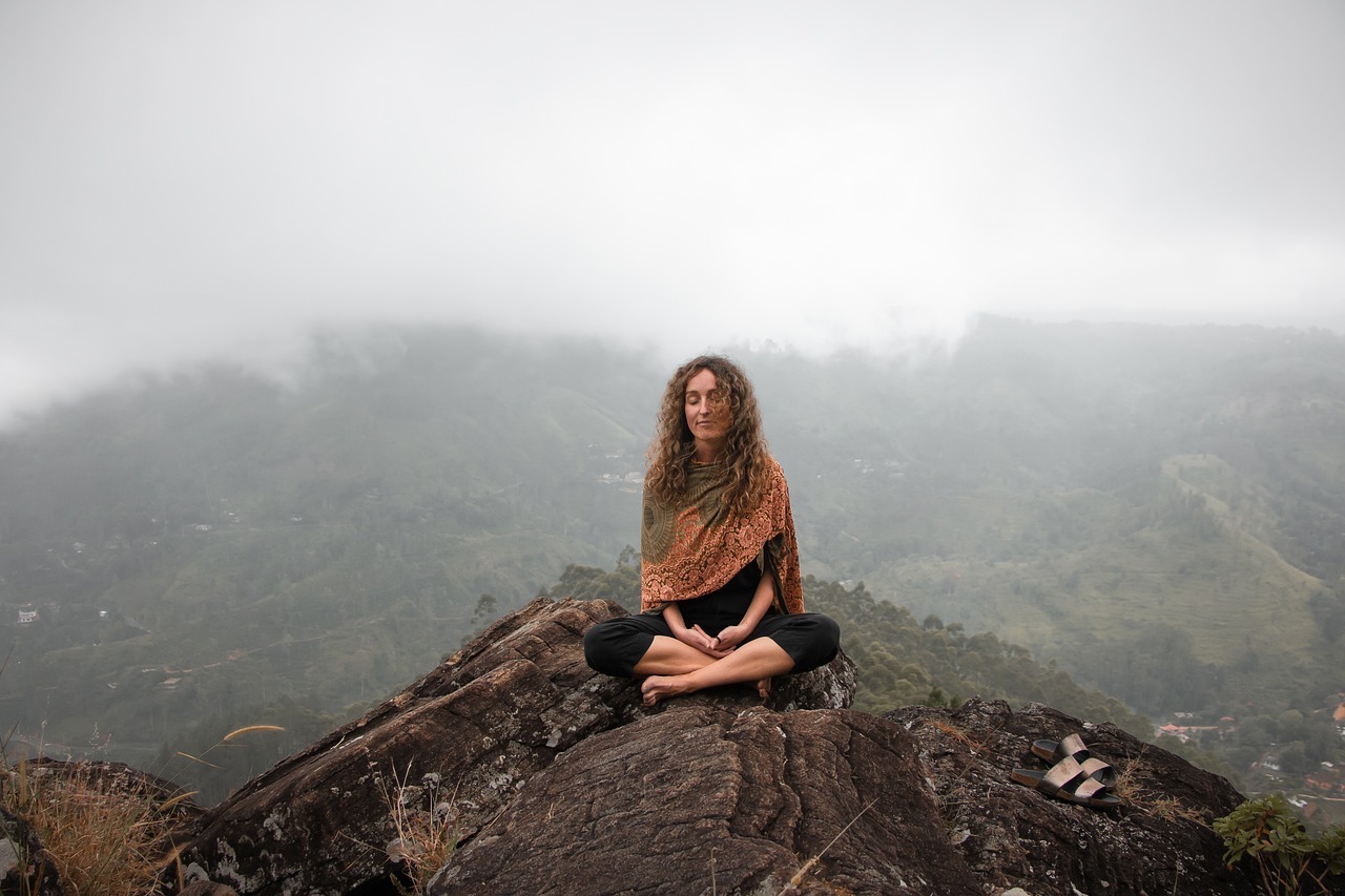 A woman sitting on a mountain peak, enjoy nature and peace of mind